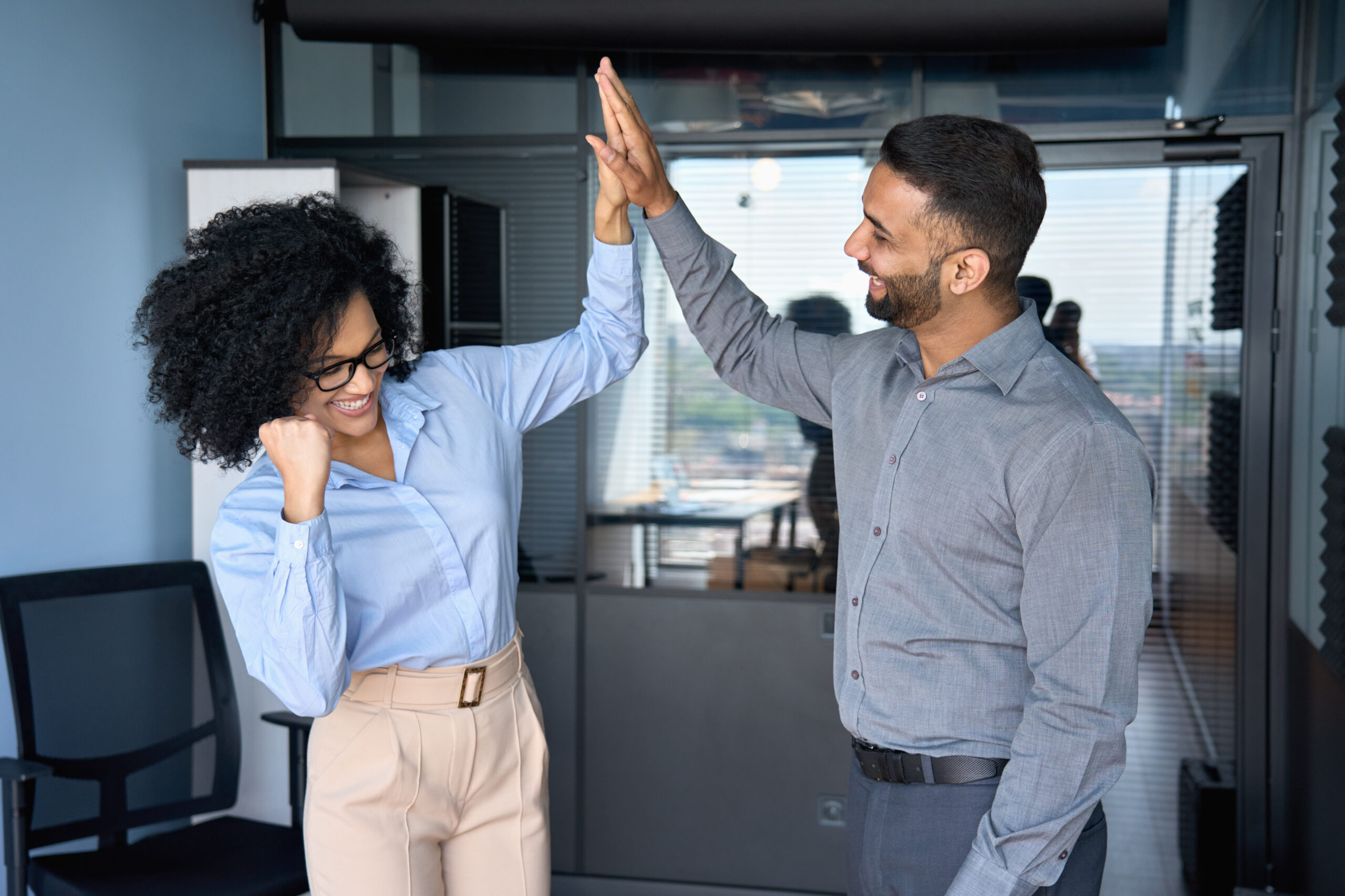 Multiracial colleagues giving high five celebrating project achievements.